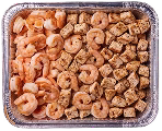 A rectangular aluminum tray filled with cooked shrimp on the left side and small, seasoned tofu cubes on the right side. The shrimp are pink and curled, while the tofu cubes are golden brown with a textured surface.