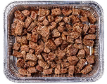 A rectangular aluminum tray filled with small, brown, cubed pieces of cooked meat, evenly spread across the surface.